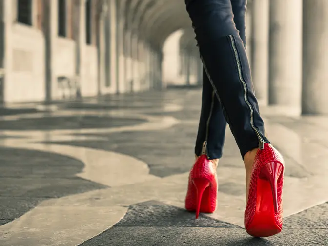 A modern woman in red high heals walking away from us symbolising The Wizard of Oz Dorothy and her red shoes 